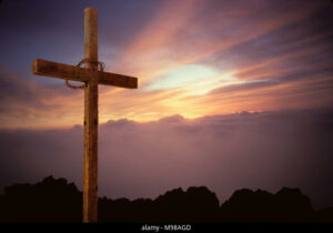 Image shows an empty cross with a crown of thorns around it. The sun is beginning to rise. 